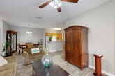 Located at 717 Burns Rd in Carrollton, GA, this single-floor residence offers a thoughtfully designed layout across two bedrooms and two bathrooms. The open-concept living area is anchored by light wood-look flooring, neutral gray walls, and a ceiling fan, creating a bright and welcoming atmosphere. A front-facing door and windows flood the living room with natural light, while the space flows seamlessly into the dining area, which features a chandelier overhead and ample room for a full dining set. The kitchen is equipped with warm wood-toned cabinetry, white appliances, and a peninsula counter that connects the cooking and living spaces. A hallway leads to both bedrooms, each carpeted and outfitted with multiple windows for natural light. The primary bedroom offers a generous footprint with room for substantial furniture, while the second bedroom is equally well-lit and comfortable. Both bathrooms feature wood-look flooring, single-sink vanities with warm wood cabinetry, and large mirrors. Two closets and two hallways contribute to the unit's practical storage and circulation. The overall ambiance is clean, functional, and inviting, making this a well-balanced residential space.