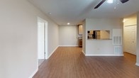 This single-floor residence offers a thoughtfully designed layout that balances comfort and functionality. The living area is a welcoming space highlighted by rich hardwood-style flooring, a ceiling fan with integrated lighting, and a set of French doors that invite natural light and provide access to the outdoors. An open pass-through connects the living area seamlessly to the kitchen, enhancing the sense of openness throughout.

The kitchen is efficiently arranged with warm wood cabinetry, granite-style countertops, and a full suite of stainless steel appliances, including a refrigerator, electric range, and over-the-range microwave. The wood-look flooring continues here, adding continuity to the space.

Two well-sized bedrooms are finished with plush carpeting and ceiling fans, each providing a comfortable and quiet retreat. One bedroom benefits from a pair of windows that allow ample natural light to filter in.

The bathroom is clean and classically styled, featuring wood-look flooring, a single-sink vanity with granite-style countertops, warm wood cabinetry, and a tub-shower combination adorned with white subway tile and a decorative diamond-pattern tile border. The overall palette of neutral tones throughout the residence creates a calm, cohesive ambiance that is both versatile and inviting.