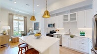 Located at 113 Vermilion Way in Collierville, TN, this well-appointed one-bedroom, one-bathroom residence offers a thoughtfully designed single-floor layout that maximizes every square foot with a clean, bright aesthetic throughout.

The kitchen is a standout feature, showcasing crisp white shaker cabinetry that extends to the ceiling, stainless steel appliances, a white quartz-topped center island, and a pair of striking gold pendant lights that add warmth and elegance to the space. Light hardwood flooring flows seamlessly through the kitchen and into the adjacent living area.

The living room is airy and inviting, benefiting from a large floor-to-ceiling window that floods the space with natural light and provides views of the surrounding neighborhood. Tall ceilings enhance the sense of openness throughout the home.

The bedroom is a tranquil retreat, featuring its own generous window with floor-to-ceiling views outdoors, soft neutral tones, and ample room for a full bedroom suite. The bathroom includes marble-look tile flooring and in-unit laundry, combining practicality with clean, modern finishes.

A hallway connects the rooms efficiently, completing a layout that is both functional and comfortable. This residence offers a polished, move-in-ready living experience in a desirable Collierville community.