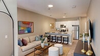 This well-appointed one-bedroom, one-bathroom residence in Birmingham, Alabama, offers a smart and efficient layout designed to maximize comfort and functionality. The open-concept living and kitchen area forms the heart of the home, where light wood-tone flooring, neutral warm-gray walls, and recessed lighting create a clean, inviting atmosphere. The kitchen is a standout feature, boasting white shaker cabinetry, granite countertops, a large peninsula island with bar seating for four, stainless steel appliances including a refrigerator, range, and microwave, and a subway tile backsplash — all illuminated by sleek pendant lights. The living area is bright and welcoming, benefiting from a glass exterior door that brings in natural light. The bedroom offers plush carpeting, a ceiling fan, a large window with outdoor views, and access to three closets that provide exceptional storage. The full bathroom features granite countertops, white cabinetry, a tiled walk-in shower, and wood-look flooring that ties seamlessly to the rest of the home. Throughout, the design strikes a balance between modern style and practical living, making this a comfortable and attractive Birmingham residence.