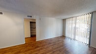 Located at 1901 E Osborne in Phoenix, Arizona, this single-floor unit offers a functional and well-organized layout throughout. The living area is bright and open, featuring warm wood-look flooring, clean white walls, and a textured ceiling. A full wall of vertical blinds covers a large sliding glass door that allows abundant natural light to fill the space and provides direct access to an outdoor patio area. A built-in shelving unit adjacent to the living room adds practical storage and display space.

The kitchen is designed for efficiency, featuring rich wood-toned cabinetry lining both sides of the galley-style layout, ample counter space, and white appliances including a refrigerator, electric range, microwave, and dishwasher. A peninsula counter with a raised bar overhang connects the kitchen to the main living area, creating an open and sociable flow between the two spaces. Track lighting illuminates the kitchen's tray ceiling detail overhead.

The bedroom is carpeted and well-sized, equipped with a ceiling fan and light fixture, and features its own sliding glass door that opens directly to a private outdoor patio, bringing in natural light and outdoor views. Throughout the unit, textured ceilings, consistent trim work, and neutral tones create a cohesive and practical living environment.