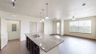 Located in Burleson, TX, this well-appointed single-story home offers two bedrooms, two bathrooms, and a thoughtfully designed layout. The open-concept kitchen and living area serves as the heart of the home, featuring rich dark cabinetry, granite countertops, a large center island with a built-in sink, pendant lighting, and black appliances including a refrigerator and range. Track lighting and hardwood-style flooring complete the inviting atmosphere, while an arched hallway adds a touch of architectural character.

Both bedrooms are carpeted and bright, each equipped with a ceiling fan and windows that invite natural light and outdoor views. The primary bedroom connects to a spacious en-suite bathroom appointed with a dark wood double vanity, ample storage cabinetry, and a separate tub and shower. The second bathroom mirrors a clean, functional design with a tub-shower combination and hardwood-style flooring.

Additional highlights include a dedicated laundry area with an in-unit washer, wire shelving for storage, and multiple closets throughout for organizational ease. The home also features a built-in desk area with granite countertop and matching dark cabinetry, ideal as a home office nook. Overall, the space presents a clean, modern aesthetic with quality finishes throughout.