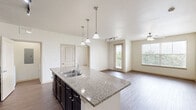 Located in Burleson, TX, this well-appointed single-story home offers two bedrooms, two bathrooms, and a thoughtfully designed layout. The open-concept kitchen and living area serves as the heart of the home, featuring rich dark cabinetry, granite countertops, a large center island with a built-in sink, pendant lighting, and black appliances including a refrigerator and range. Track lighting and hardwood-style flooring complete the inviting atmosphere, while an arched hallway adds a touch of architectural character.

Both bedrooms are carpeted and bright, each equipped with a ceiling fan and windows that invite natural light and outdoor views. The primary bedroom connects to a spacious en-suite bathroom appointed with a dark wood double vanity, ample storage cabinetry, and a separate tub and shower. The second bathroom mirrors a clean, functional design with a tub-shower combination and hardwood-style flooring.

Additional highlights include a dedicated laundry area with an in-unit washer, wire shelving for storage, and multiple closets throughout for organizational ease. The home also features a built-in desk area with granite countertop and matching dark cabinetry, ideal as a home office nook. Overall, the space presents a clean, modern aesthetic with quality finishes throughout.