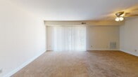 Located at 3347 Hewitt Ave in Silver Spring, MD, this second-floor apartment presents a practical and comfortable single-level layout. The spacious living area is finished with warm beige carpeting and features a large vertical-blind window treatment that allows for generous natural light and easy light control. A pass-through opening connects the living space to the kitchen, which is equipped with light wood cabinetry, granite-style countertops, a black gas range with overhead ventilation, and ample storage throughout. The bedroom areas also feature soft wall-to-wall carpeting and neutral cream-toned walls, creating a calm and versatile atmosphere. One bedroom benefits from direct access to a private bathroom, offering added convenience. Both bathrooms are finished with hardwood-style flooring, wood-toned vanity cabinetry, large wall mirrors with overhead lighting, and clean white fixtures. The overall design of the unit is clean and understated, with consistent neutral tones, white trim, and a straightforward floor plan that maximizes usable space. The layout, as revealed by the dollhouse view, reflects a well-organized configuration well-suited for comfortable everyday living in the Silver Spring area.