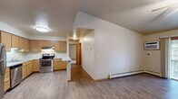 Located at 2200 Nicolet Dr in Green Bay, Wisconsin, this two-bedroom, one-bathroom unit offers a well-organized, single-floor layout with a practical and comfortable design throughout. The open-concept kitchen and living area serves as the heart of the home, featuring warm honey-toned wood cabinetry, light granite-style countertops, a peninsula breakfast bar, and a full suite of stainless steel appliances including a refrigerator, electric range, and dishwasher. A chandelier over the dining area and flush-mount lighting in the kitchen add functional brightness. The spacious living room is finished with durable wood-look flooring, a ceiling fan, baseboard heating, and a sliding glass door that fills the room with natural light and provides access to an outdoor space with views of surrounding greenery. Both bedrooms are carpeted for comfort; the primary bedroom is generously sized and includes a large walk-in closet with built-in shelving, while the second bedroom features a window with natural light and a sliding double-door closet. The full bathroom is appointed with a single-sink vanity with wood cabinetry, a lighted mirror, and a tub-shower combination. Wood-tone doors and trim carry a consistent, cohesive aesthetic throughout the entire unit.