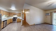 Located at 2200 Nicolet Dr in Green Bay, Wisconsin, this two-bedroom, one-bathroom unit offers a well-organized, single-floor layout with a practical and comfortable design throughout. The open-concept kitchen and living area serves as the heart of the home, featuring warm honey-toned wood cabinetry, light granite-style countertops, a peninsula breakfast bar, and a full suite of stainless steel appliances including a refrigerator, electric range, and dishwasher. A chandelier over the dining area and flush-mount lighting in the kitchen add functional brightness. The spacious living room is finished with durable wood-look flooring, a ceiling fan, baseboard heating, and a sliding glass door that fills the room with natural light and provides access to an outdoor space with views of surrounding greenery. Both bedrooms are carpeted for comfort; the primary bedroom is generously sized and includes a large walk-in closet with built-in shelving, while the second bedroom features a window with natural light and a sliding double-door closet. The full bathroom is appointed with a single-sink vanity with wood cabinetry, a lighted mirror, and a tub-shower combination. Wood-tone doors and trim carry a consistent, cohesive aesthetic throughout the entire unit.