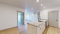 Located in Spokane, WA, this thoughtfully designed 2-bedroom, 2-bathroom unit offers a clean, modern aesthetic across a single level. The open-concept layout connects the kitchen and living room seamlessly, creating a bright and functional living space. The kitchen is a standout feature, showcasing a large center island with a quartz countertop and an undermount sink with a modern pull-down faucet, crisp white shaker cabinets with matte black hardware, and a full suite of stainless steel appliances including a range, microwave, and refrigerator. Recessed lighting and a wall-mounted mini-split system add comfort and efficiency. Light-toned hardwood-style flooring runs throughout the unit, lending warmth and continuity to every room. The living area offers access to the outdoors through a glass-paneled door, with windows framing views of the surrounding neighborhood greenery. Both bedrooms are generously sized, bathed in natural light from dual-pane windows with blinds, and include dedicated closet space. The spacious primary bedroom provides ample room for a full furniture arrangement. The two bathrooms are finished with white shaker-style vanities, matte black fixtures, and clean tile surrounds. A convenient in-unit laundry area with a full-size washer and dryer is tucked alongside one of the bathrooms, adding everyday practicality to this well-appointed home.