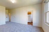 Located at 903 Union St in the heart of Seattle, WA, this one-bedroom, one-bathroom unit offers a well-organized layout across a single floor. The generously sized bedroom is the centerpiece of the space, featuring soft wall-to-wall carpeting, bright white walls, and a large window that frames views of the surrounding cityscape and greenery. A classic cast-iron radiator provides warmth, adding a touch of historic character to the room. A walk-in closet off the bedroom offers a dedicated hanging rod and shelving, providing practical storage. The compact kitchen is efficiently designed, featuring warm wood-toned cabinetry and a full-size refrigerator, with hardwood-style flooring that contrasts nicely with the carpeted living areas. The bathroom is clean and functional, showcasing a pedestal sink, a tiled soaking tub with shower, and wood-style flooring. Neutral tones and white surfaces throughout the unit create a bright, cohesive aesthetic. An intercom system is conveniently mounted near the entry. This unit combines classic Seattle building character with a practical, livable floor plan in a prime Union Street location.