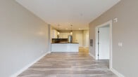 Located at 1135 Post Rd E in Westport, CT, this well-appointed one-bedroom, one-bathroom unit offers a thoughtfully designed single-floor layout with modern finishes throughout. The open-concept kitchen serves as a central gathering point, featuring white shaker-style cabinetry, a grey subway tile backsplash, dark countertops, and a peninsula with pendant lighting. Stainless steel appliances, including a gas range, microwave, and refrigerator, complete the sleek culinary space, which flows seamlessly into the living area over light-toned hardwood-style flooring. The generously sized primary bedroom is carpeted for comfort and bathed in natural light from a large bank of windows offering views of the surrounding greenery. Two closets — one of which is a walk-in style — provide excellent storage solutions. The bathroom is finished with large-format grey floor tiles, a glass-enclosed walk-in shower with clean white surround, and a window that brings in natural light. Neutral grey tones, clean white trim, and recessed lighting are carried throughout the unit, creating a cohesive and contemporary ambiance suited for comfortable everyday living in the heart of Westport.