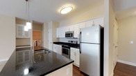 Located at 5303 Wilcox Rd in Dublin, Ohio, this single-floor residence offers a well-appointed, contemporary layout designed for comfortable everyday living. The kitchen is a standout feature, showcasing crisp white shaker-style cabinetry, dark granite countertops, and a full suite of stainless steel appliances including an electric range, built-in microwave, and refrigerator. A peninsula with an undermount sink adds both workspace and a natural gathering point, while rich dark hardwood-style flooring grounds the area with a polished, modern aesthetic. The open sightlines from the kitchen extend into the main living corridor, where multiple white panel doors lead to additional rooms. The bedrooms are generously sized, finished with plush wall-to-wall carpeting, neutral warm-toned walls, and ceiling fans for year-round comfort. Windows with blinds allow natural light to fill these rooms. The bathrooms are finished with matching dark granite vanity tops, white cabinetry, framed mirrors, and tile flooring. One bathroom features a full tub-shower combination. A dedicated in-unit laundry area with full-size washer and dryer adds everyday convenience. Spacious walk-in closet storage with wire shelving completes this thoughtfully designed residence.