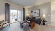 Located in Lockport, IL, this single-floor residence offers a thoughtfully designed layout that balances comfort and functionality. The living room serves as the heart of the home, featuring plush carpeting, a sliding glass door that opens to a private balcony with outdoor views, and ample space for relaxed seating arrangements. Natural light flows in generously through the large glass door, enhancing the warm, neutral color palette throughout.

The kitchen is outfitted with white shaker-style cabinetry, granite countertops, stainless steel appliances including a gas range and refrigerator, and durable wood-look flooring — a clean, efficient space well-suited for everyday cooking.

The primary bedroom is a serene retreat, highlighted by a sage green accent wall, a large window with plantation shutters that invite in abundant natural light, and soft carpeting underfoot. A secondary bedroom features crisp white walls, carpeted floors, and stylish mid-century modern furnishings. The bathroom offers wood-look vinyl flooring, granite-topped vanity, and a clean, minimal aesthetic.

A dedicated dining and office nook provides a versatile space for working from home or casual meals, with built-in desk space and room for a dining set. Throughout the residence, the design maintains a cohesive contemporary style with neutral tones and modern finishes.