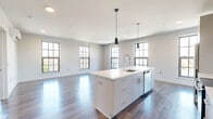 Located at 75 S Main St in Norwalk, CT, this well-designed 2-bedroom, 2-bathroom residence offers a thoughtfully planned single-floor layout filled with contemporary finishes throughout. Rich hardwood flooring flows seamlessly across the entire living space, anchoring the clean, modern aesthetic.

The open-concept kitchen and living area serves as the heart of the home. The kitchen is outfitted with sleek white cabinetry, a white quartz waterfall island with an integrated sink, stainless steel appliances including a refrigerator, range, microwave, and dishwasher, and a white subway tile backsplash. Stylish pendant lighting accents the island, while large gridded windows flood the space with abundant natural light and city views.

The generously sized primary bedroom features sliding glass doors opening onto a private balcony with neighborhood views, a wall-mounted mini-split unit, and a dedicated walk-in closet with wire shelving. The second bedroom also benefits from multiple large windows and a wall-mounted climate unit. Both bedrooms are served by well-appointed bathrooms — one with warm hardwood-style flooring, a vanity, and a soaking tub, the other with large-format tile flooring and a walk-in shower. A dedicated laundry area and two closets complete this polished residence.