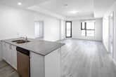 Located at 30 Hanmer St W in Barrie, Ontario, this modern unit offers a thoughtfully designed open-concept layout finished in a clean, contemporary style throughout. Light-toned luxury vinyl plank flooring flows seamlessly across the entire space, complementing the crisp white walls and creating a bright, airy atmosphere.

The kitchen serves as a functional centrepiece, featuring white shaker-style cabinetry, quartz countertops, stainless steel appliances including a refrigerator, electric range, and built-in microwave, as well as a large island with a double undermount sink — ideal for both cooking and casual dining.

The open living area is generously proportioned, bathed in natural light through large black-framed windows that frame views of the surrounding Barrie landscape. A patio door provides direct access to an outdoor balcony, extending the living space further.

The primary bedroom includes a walk-in closet and a private ensuite bathroom, offering a practical and comfortable retreat. An additional bedroom features expansive black-framed windows with scenic outdoor views. The full main bathroom is finished with a soaker tub and shower combination, a vanity with quartz countertop, and a large mirror. Recessed lighting and roller blinds complete the polished, move-in-ready presentation of this well-appointed space.