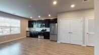 This thoughtfully designed single-floor space offers a clean, modern aesthetic throughout. The open-concept living and kitchen area is anchored by rich dark cabinetry, granite countertops, and a classic white subway tile backsplash. The kitchen is fully equipped with a complete suite of stainless steel appliances, including a refrigerator, range, over-the-range microwave, and dishwasher, providing both style and functionality. Recessed lighting illuminates the space efficiently, complementing the warm, light-toned luxury vinyl plank flooring that runs throughout the main living areas. The spacious living area offers generous room for furnishings and features neutral gray walls that contribute to a calm, versatile ambiance. A bedroom features a large window that invites natural light and offers exterior views, creating a bright and welcoming retreat. The bathroom is finished with matching dark cabinetry, a granite-topped vanity, a large mirror, and light-toned tile flooring. Notably, the bathroom includes accessibility-friendly grab bars, reflecting a thoughtful approach to inclusive design. A double-door closet provides ample storage within the unit. The overall design is cohesive and contemporary, with consistent finishes and a neutral palette throughout.