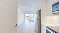 This thoughtfully designed 3-bedroom, 2-bathroom unit offers a clean, contemporary aesthetic throughout its single-floor layout. Light hardwood flooring flows seamlessly across every room, complementing the crisp white walls and creating a bright, cohesive atmosphere.

The open-concept living and kitchen area forms the heart of the unit. The kitchen is outfitted with sleek, floor-to-ceiling white cabinetry and stainless steel appliances, including a full-size refrigerator. Double glass doors connect the living space directly to a private balcony, inviting abundant natural light and outdoor views into the interior.

The generously sized primary bedroom offers ample space and is well-lit by natural light. The two additional bedrooms are efficiently laid out with large windows that frame urban views, making them well-suited as guest rooms or a home office. Sliding and hinged panel doors provide a clean, modern touch throughout the hallways and rooms.

Both bathrooms maintain the unit's minimalist design language, each featuring a soaker tub and shower combination, white vanity cabinetry, and a large mirror. The hallway connecting the bedrooms and bathrooms is bright and accessible, with mirrored closet doors adding depth.

Overall, the unit presents a modern, move-in-ready space defined by clean lines, natural light, and functional design.