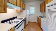 Located at 74 Rogers Ln in Middletown, Rhode Island, this single-floor home offers a straightforward, functional layout with neutral finishes throughout. The interior is organized into clearly defined living spaces connected by white six-panel doors and consistent design elements.

The bedrooms feature plush gray carpeting, white walls, and built-in closets with standard rod storage. Natural light filters in through windows framing views of surrounding greenery, lending the rooms a calm, connected-to-nature atmosphere. One bedroom includes an electrical panel, and several rooms feature floor vents for climate control.

The kitchen is efficiently designed in a galley configuration, with warm wood-toned cabinetry lining both walls, light wood-look flooring, and white appliances including a gas range, refrigerator, and dishwasher. A sink with ample counter space sits beneath upper cabinets, and a windowed exterior door provides additional natural light and outdoor access.

The bathroom includes a full tub and shower combination with white tile surround and a window overlooking the greenery outside, maintaining the home's consistent access to natural light. Overall, the space presents a clean, move-in-ready environment with a practical layout suited to everyday living.