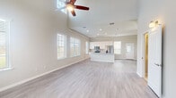 Located at 9913 Crescent Cove Dr in Montgomery, Texas, this two-story home offers a thoughtfully designed layout with clean, modern finishes throughout. The main living area impresses with soaring vaulted ceilings, light wood-look flooring, and an abundance of natural light streaming through multiple windows fitted with classic white blinds. A ceiling fan anchors the open living space, which flows seamlessly into the kitchen. The kitchen is well-equipped with white cabinetry, granite countertops, a subway tile backsplash, stainless steel appliances including a range, over-the-range microwave, and refrigerator, along with a central island for added workspace. A convenient half bathroom with tile flooring is tucked under the staircase. The bedrooms feature plush carpeting and generous closet space, with several rooms offering walk-in closets. The primary bedroom includes a ceiling fan and direct access to an en-suite bathroom. Bathrooms are finished with tile flooring, white vanities topped with granite countertops, and large mirrors. The primary bath features a dual-sink vanity. The home's neutral color palette and consistent use of quality materials create a bright, cohesive ambiance throughout both floors.