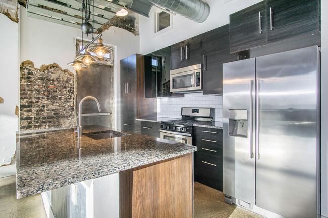 Granite countertops, stainless steel appliances and dark contemporary cabinets - Ideal Building