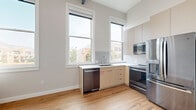Located at 1108 Washington Ave in Golden, CO, this thoughtfully designed two-bedroom, one-bathroom residence offers a modern aesthetic with clean lines and quality finishes throughout. The single-floor layout makes efficient use of space, connecting each room through a central hallway lined with stylish louvered and paneled doors featuring sleek matte black hardware.

The kitchen is a functional highlight, equipped with stainless steel appliances including a refrigerator, range, built-in microwave, and dishwasher. Warm, neutral cabinetry pairs with a white countertop and a window-flanked sink, bathing the space in natural light with views of the surrounding Golden streetscape.

The primary bedroom features light hardwood flooring and a ceiling fan, offering a bright and airy atmosphere. The secondary bedroom is carpeted in a neutral tone, providing a soft, comfortable feel. Both bedrooms are serviced by two dedicated closets for ample storage.

The bathroom is sleek and modern, with large-format tile flooring, a floating vanity with an undermount sink and white countertop, a frameless glass-enclosed shower, and brushed nickel fixtures. A dedicated laundry area adds everyday convenience. Neutral wall tones and consistent design elements create a cohesive, contemporary ambiance throughout the home.