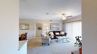 This single-floor residence offers a thoughtfully arranged layout that balances comfort and functionality across several distinct living spaces. The living room serves as the heart of the home, featuring plush wall-to-wall carpeting, crown molding, a ceiling fan with light fixture, and a gas fireplace framed by a clean white mantel. Sliding glass doors with vertical blinds open to a private outdoor balcony, allowing natural light to fill the room. A dedicated dining area adjacent to the living space accommodates a full-sized dining table and is accented with crown molding and framed wall art.

The kitchen is equipped with light wood cabinetry extending to the ceiling, ample countertop workspace, a double-basin sink, a full suite of white appliances including a range, over-the-range microwave, and refrigerator, as well as wood-look flooring for easy maintenance.

The bedrooms are carpeted and well-lit, each featuring a ceiling fan, vertical blinds, and windows that bring in natural light. The bathroom includes a wide, full-width vanity mirror, a speckled countertop with an undermount sink, tiled shower-tub combination, and wood-look flooring, delivering a clean and practical design throughout.