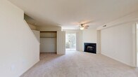 Located at 900 Clubhouse Pl in Harrisburg, PA, this two-story, two-bedroom, two-bathroom home offers a thoughtfully arranged floor plan spread across two levels. The main floor comprises the majority of the living space, including a combined kitchen and living room, hallway, and closet storage. The living room is a standout area, featuring plush carpeting, a ceiling fan, a sleek fireplace with a dark surround, and a sliding glass door that floods the space with natural light and provides outdoor access. The kitchen includes warm wood cabinetry, granite-style countertops, a stainless steel dishwasher, and durable wood-look flooring, along with a recessed ceiling light. Both bedrooms are carpeted and equipped with ceiling fans. The primary bedroom benefits from large windows offering views of the surrounding greenery and includes a walk-in closet with built-in shelving. The bathrooms feature tile flooring, wood vanities with white countertops, and a tub-shower combination. Additional utility and storage areas are present, currently in a renovation state with drywall and concrete flooring. A staircase connects the two levels, completing this functional and comfortable home.