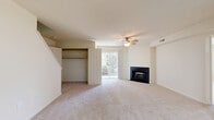 Located at 900 Clubhouse Pl in Harrisburg, PA, this two-story, two-bedroom, two-bathroom home offers a thoughtfully arranged floor plan spread across two levels. The main floor comprises the majority of the living space, including a combined kitchen and living room, hallway, and closet storage. The living room is a standout area, featuring plush carpeting, a ceiling fan, a sleek fireplace with a dark surround, and a sliding glass door that floods the space with natural light and provides outdoor access. The kitchen includes warm wood cabinetry, granite-style countertops, a stainless steel dishwasher, and durable wood-look flooring, along with a recessed ceiling light. Both bedrooms are carpeted and equipped with ceiling fans. The primary bedroom benefits from large windows offering views of the surrounding greenery and includes a walk-in closet with built-in shelving. The bathrooms feature tile flooring, wood vanities with white countertops, and a tub-shower combination. Additional utility and storage areas are present, currently in a renovation state with drywall and concrete flooring. A staircase connects the two levels, completing this functional and comfortable home.
