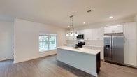 Located at Westfield Green in Selden, NY, this two-story home offers a thoughtfully designed layout with contemporary finishes throughout. The main level features an open-concept living and dining area with smooth hardwood-style flooring, crisp white walls, and abundant natural light streaming through multiple windows that overlook a deck and surrounding greenery. The well-appointed kitchen is a standout, showcasing a large center island with a striking marble-look quartz countertop and an integrated sink, complemented by white shaker-style cabinetry, a white subway tile backsplash, and a full suite of stainless steel appliances including a gas range, over-the-range microwave, and French door refrigerator. Pendant lighting above the island adds a refined touch. A convenient half bath with a pedestal sink and round mirror rounds out the main floor. Upstairs, the bedrooms feature plush carpeting and generous windows that bring in natural light and views of the neighborhood. The primary bathroom is well-equipped with a double-sink vanity, a separate glass-enclosed shower, and a soaking tub with tiled surround. A second full bathroom mirrors the clean aesthetic with subway tile and a dark wood vanity. This home combines modern design with functional living spaces throughout.
