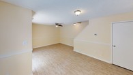 This two-story property in Reno offers a practical and functional layout across two levels. The main living area on the ground floor is spacious and open, featuring light hardwood-style flooring that runs throughout. Warm, neutral yellow-toned walls create a bright and welcoming atmosphere, complemented by a textured ceiling and ceiling fans that provide both lighting and airflow. A staircase leads to the upper level, adding architectural structure to the living space. Sliding glass doors open directly to an outdoor patio area, providing views of a fenced backyard and surrounding greenery, allowing natural light to flow freely into the interior. A narrow side window further enhances the light within the main living area.

The bedrooms are carpeted in a neutral tan tone and feature windows fitted with horizontal blinds, offering views of the surrounding trees and vegetation. These rooms are well-proportioned, clean, and functional, with textured ceilings consistent throughout the home. White trim and baseboards frame each room neatly. Overall, the property presents a clean, move-in-ready environment with a cohesive warm color palette and a comfortable, livable ambiance across both floors.