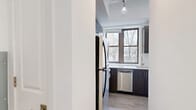 Located at 201 Cornelison Avenue in Jersey City, NJ, this thoughtfully designed unit offers a clean, modern aesthetic across a single floor. The open-plan kitchen and living area serves as the heart of the space, bathed in natural light from multiple large windows that frame views of surrounding greenery. Light-toned hardwood-style flooring and crisp white walls create a bright, airy atmosphere, while a stylish pendant light adds a decorative focal point overhead.

The kitchen is well-appointed with dark wood cabinetry, sleek white quartz countertops, and a classic white subway tile backsplash. Stainless steel appliances — including a gas range, microwave, dishwasher, and refrigerator — provide a modern, functional finish. A stainless steel sink with a contemporary gooseneck faucet sits beneath a window, enhancing the workspace with natural light.

The bathroom is finished in a neutral palette, featuring wood-look tile flooring, a tub-shower combination with white tile surround, a modern vanity with a mirrored medicine cabinet, and soft overhead lighting. Two closets offer practical storage solutions, and a dedicated laundry area adds everyday convenience. This well-designed unit blends style and functionality seamlessly.