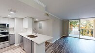 This thoughtfully updated single-floor residence offers a clean, contemporary aesthetic throughout. The open-concept layout connects the kitchen and living area seamlessly, creating a bright and functional living space. The kitchen is a standout feature, equipped with stainless steel appliances including a refrigerator with ice maker, range, and over-the-range microwave. Two-tone cabinetry — white uppers and grey lowers — pairs with white quartz countertops and a peninsula island with an undermount sink, offering both prep space and a casual dining option. Crown molding and recessed lighting add refined detail to the main living area, which extends to a private balcony with outdoor views.

Wood-style luxury vinyl plank flooring runs throughout the residence, lending warmth and continuity to every room. The bedrooms are generously sized, each featuring ceiling fans and natural light from large windows with blinds. Both bathrooms are tastefully updated with white vanities, quartz countertops, undermount sinks, and well-lit mirrors. A dedicated laundry area houses a full-size side-by-side washer and dryer with overhead wire shelving for added storage. The overall palette of soft grey and white tones creates a calm, modern ambiance throughout.