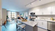 This well-appointed 2-bedroom, 2-bathroom residence offers a thoughtfully designed single-level layout with contemporary finishes throughout. The open-concept kitchen and living area serves as the heart of the home, anchored by a large central island with seating — ideal for casual dining or entertaining. The kitchen is outfitted with stainless steel appliances, including a gas range, microwave, dishwasher, and French door refrigerator, complemented by crisp white cabinetry, quartz countertops, and a herringbone tile backsplash. Track lighting overhead adds a modern, functional touch. Wood-style flooring runs throughout the main living area, which features large windows that invite natural light and outdoor views.

The primary bedroom offers a comfortable, well-scaled retreat with soft carpeting, track lighting, and a dedicated closet featuring double hanging rods for ample storage. The second bedroom similarly benefits from generous natural light through large windows and urban views. Both bathrooms are finished with clean white subway tile, including a soaking tub. A stacked in-unit washer and dryer provides added convenience, and a hallway connects all rooms for a cohesive, efficient flow throughout the residence.
