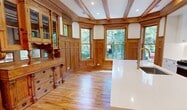 Located in Chicago's vibrant Ukrainian Village neighborhood, Unit 1 at 1233 N Hoyne Avenue offers 1,640 square feet of thoughtfully designed single-floor living across 5 bedrooms and 4 bathrooms. Throughout the unit, warm hardwood floors and rich oak trim create a cohesive craftsman aesthetic. The kitchen is a standout feature, boasting exposed wood ceiling beams, white shaker cabinetry, stainless steel appliances, and a large center island with a white quartz countertop and wood base — all illuminated by recessed lighting. The living area connects openly to the kitchen and is anchored by a striking bay window that floods the space with natural light and neighborhood views. Each bedroom features hardwood floors, oak door and window casings, and ample natural light, with several rooms offering views of tree-lined surroundings. The primary bedroom spans 130 square feet. The four bathrooms are finished with marble-look tile flooring, subway tile, gray vanities with marble countertops, and oak-framed mirrors — combining classic and modern sensibilities. Five closets provide generous storage throughout. The unit's consistent use of warm wood tones, crown molding, and quality finishes delivers a refined yet inviting atmosphere.