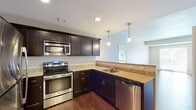 This single-floor residence offers a thoughtfully designed layout that balances functionality and comfort throughout. The open-concept living and dining area is anchored by rich hardwood flooring that flows seamlessly toward the kitchen, creating a cohesive and inviting atmosphere.

The kitchen is a standout feature, showcasing dark espresso cabinetry, granite countertops, and a full suite of stainless steel appliances — including a refrigerator, electric range, microwave, and dishwasher. Pendant lighting above the peninsula adds a polished touch, while recessed lighting illuminates the workspace efficiently.

The bedrooms are finished with plush wall-to-wall carpeting and neutral tones, offering a calm and restful environment. One bedroom benefits from a window with outdoor views, filling the room with natural light. A spacious walk-in closet with built-in wire shelving and hanging rods provides generous storage.

The bathrooms continue the design language of the kitchen, featuring matching dark vanity cabinetry, granite countertops, and wood-look flooring. The primary bath includes a glass-enclosed shower and a dedicated vanity area, while a second bathroom provides additional convenience.

Overall, the space presents a clean, modern aesthetic with consistent finishes and practical design elements throughout.