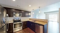 This single-floor residence offers a thoughtfully designed layout that balances functionality and comfort throughout. The open-concept living and dining area is anchored by rich hardwood flooring that flows seamlessly toward the kitchen, creating a cohesive and inviting atmosphere.

The kitchen is a standout feature, showcasing dark espresso cabinetry, granite countertops, and a full suite of stainless steel appliances — including a refrigerator, electric range, microwave, and dishwasher. Pendant lighting above the peninsula adds a polished touch, while recessed lighting illuminates the workspace efficiently.

The bedrooms are finished with plush wall-to-wall carpeting and neutral tones, offering a calm and restful environment. One bedroom benefits from a window with outdoor views, filling the room with natural light. A spacious walk-in closet with built-in wire shelving and hanging rods provides generous storage.

The bathrooms continue the design language of the kitchen, featuring matching dark vanity cabinetry, granite countertops, and wood-look flooring. The primary bath includes a glass-enclosed shower and a dedicated vanity area, while a second bathroom provides additional convenience.

Overall, the space presents a clean, modern aesthetic with consistent finishes and practical design elements throughout.