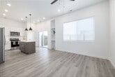 Located at 4107 Laster Ln in Caldwell, Idaho, this single-story one-bedroom, one-bathroom home offers a thoughtfully designed layout that maximizes every square foot. Light wood-look flooring flows throughout the open living areas, creating a warm and cohesive aesthetic.

The kitchen is a standout feature, showcasing white shaker cabinetry, bright quartz countertops, and a full suite of stainless steel appliances including a French door refrigerator, electric range with microwave, and dishwasher. A central island with a contrasting wood-toned base provides additional prep space and casual seating, while modern pendant lighting with gold-toned interiors adds a stylish touch overhead. Recessed lighting and high ceilings further enhance the open, airy feel of the space.

The bedroom is a bright, clean room filled with natural light through a window fitted with classic white blinds, with the same light flooring continuing throughout. A private outdoor area with a patch of green turf and gravel landscaping is visible from the dollhouse view, offering a functional exterior space.

The bathroom features a clean, minimalist design with white subway tile, a glass-panel shower enclosure with matte black hardware, and a window that brings in natural light. Hallways connect the rooms efficiently, completing this well-organized and modern single-floor home.