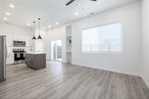 Located at 4107 Laster Ln in Caldwell, Idaho, this single-story one-bedroom, one-bathroom home offers a thoughtfully designed layout that maximizes every square foot. Light wood-look flooring flows throughout the open living areas, creating a warm and cohesive aesthetic.

The kitchen is a standout feature, showcasing white shaker cabinetry, bright quartz countertops, and a full suite of stainless steel appliances including a French door refrigerator, electric range with microwave, and dishwasher. A central island with a contrasting wood-toned base provides additional prep space and casual seating, while modern pendant lighting with gold-toned interiors adds a stylish touch overhead. Recessed lighting and high ceilings further enhance the open, airy feel of the space.

The bedroom is a bright, clean room filled with natural light through a window fitted with classic white blinds, with the same light flooring continuing throughout. A private outdoor area with a patch of green turf and gravel landscaping is visible from the dollhouse view, offering a functional exterior space.

The bathroom features a clean, minimalist design with white subway tile, a glass-panel shower enclosure with matte black hardware, and a window that brings in natural light. Hallways connect the rooms efficiently, completing this well-organized and modern single-floor home.