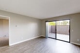Located at 81875 Avenue 48 in Indio, CA, this single-story 1-bedroom, 1-bathroom unit offers a thoughtfully organized floor plan across a compact yet functional footprint. The open-concept living and dining area is finished with light wood-style hard flooring, neutral warm-gray walls, and clean white baseboards, creating a bright and cohesive aesthetic. A sliding glass door floods the living space with natural light and opens directly onto a private enclosed patio, providing a seamless indoor-outdoor connection. A ceiling fan is installed in the main living area for added comfort. The galley-style kitchen features white cabinetry, a countertop with an integrated sink, and a full suite of white appliances including a refrigerator, range, microwave, and dishwasher, all beneath a flush ceiling light panel. The spacious primary bedroom is carpeted for comfort and includes a large window with vertical blinds for natural light and privacy, along with two closets for ample storage. The bathroom is cleanly appointed with a full tub-shower combo, a vanity with a speckled countertop, and wood-style flooring. Additional conveniences include an in-unit laundry area, a thermostat, and ample wall outlets throughout.