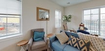 This single-floor residence offers a thoughtfully designed layout with a clean, modern aesthetic evident throughout its interconnected spaces. The kitchen is outfitted with stainless steel appliances, including a gas range, over-the-range microwave, and refrigerator, complemented by light wood cabinetry, marble-style countertops, and a classic white subway tile backsplash with decorative mosaic accents. Light wood-style flooring runs through the kitchen and main living areas, contributing to a bright, cohesive feel.

The living area provides a comfortable, welcoming space with natural light filtering through multiple windows dressed with blinds. A dining area sits adjacent, creating a seamless open flow suited for everyday living and entertaining.

The bedroom is generously proportioned with plush carpeting, multiple windows allowing ample natural light, and sufficient room for a sizable furniture arrangement. A secondary carpeted room, visible from the bedroom corridor, offers flexible use as an additional bedroom or sitting area, with direct sightlines to the kitchen beyond.

The bathroom features a tub-shower combination with full subway tile surround and decorative border, complemented by stone-look tile flooring, a modern vanity with light wood cabinetry, and a mirrored medicine cabinet. Neutral tones and clean lines define the overall aesthetic of this well-maintained residence.