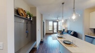 Located at 930 Jones Franklin Rd in Raleigh, NC, this single-floor unit offers a well-designed open-concept layout that seamlessly connects the kitchen, dining, and living areas. Rich wood-tone flooring runs throughout the main living spaces, anchoring the contemporary aesthetic and providing a warm contrast to the neutral wall tones.

The kitchen is outfitted with white shaker-style cabinetry, a dark slate tile backsplash, stainless steel appliances — including a French door refrigerator, electric range, built-in microwave, and dishwasher — and a light-toned extended island that doubles as a dining surface, illuminated by globe pendant lights. A dedicated mudroom entry near the front door features built-in shelving, wall hooks, and beadboard paneling for organized storage.

The living area benefits from natural light through a large window and sliding door leading to a balcony, complemented by a ceiling fan overhead. The bedroom is carpeted and features a generous window with outdoor views and its own ceiling fan. The bathroom presents marble-look tile flooring, a wide vanity with ample cabinetry, and a glass-enclosed shower-tub combination, offering a clean and refined finish throughout.