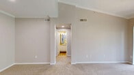 This single-floor, 2-bedroom, 2-bathroom residence at 9301 Spectrum Dr offers a practical and comfortable layout across a well-utilized footprint. The open kitchen is a standout feature, equipped with white shaker-style cabinetry, granite-look countertops, a peninsula with a double sink, and a full suite of stainless steel appliances including a refrigerator, microwave, and range. Wood-look flooring runs through the kitchen and main areas, transitioning to plush carpet in the living spaces and bedrooms. The living room is bright and airy, highlighted by a ceiling fan, crown molding, and a sliding glass door that opens to an outdoor balcony with views of surrounding greenery. The primary bedroom is generously sized and includes a walk-in closet with wire shelving. The second bedroom features a ceiling fan and a window with natural light and outdoor views. Both bathrooms offer tub/shower combinations with white tile surrounds and chrome fixtures. A dedicated in-unit laundry room accommodates a full-size side-by-side washer and dryer with overhead wire shelving. A hallway connects the bedrooms and bathrooms, providing a clean, organized flow throughout the home. Neutral wall tones and consistent finishes lend a cohesive, move-in-ready ambiance.