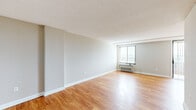 Located at 2000 Huntington Ave in Alexandria, Virginia, this single-story residence offers three bedrooms, one bathroom, and a thoughtfully arranged floor plan that makes efficient use of its space. Warm-toned hardwood flooring runs consistently throughout the unit, lending a cohesive and inviting character to every room.

The living room is generously proportioned, featuring neutral gray walls, a textured ceiling, and a large window fitted with blinds that allows ample natural light to fill the space. A wall-mounted HVAC unit provides climate control. The layout flows through a central hallway connecting the bedrooms and shared spaces.

Each bedroom is well-sized with the same hardwood flooring, neutral walls, and windows offering exterior views. The spacious primary bedroom includes a closet. The additional bedrooms offer clean, open layouts suitable for various uses.

The kitchen features rich medium-toned wood cabinetry with glass-front upper cabinets, dark granite countertops, a stainless steel sink, and hardwood flooring — offering both style and practicality. The bathroom includes a full tub-shower combination with white subway tile surround and clean white finishes throughout.