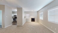 This two-floor residence offers a well-organized layout with thoughtfully selected finishes throughout. The main living area greets visitors through a paneled front door, opening into a spacious, carpet-floored room filled with natural light from multiple windows fitted with white blinds. The living space flows toward a tile-surround fireplace, providing a functional focal point, while a track lighting fixture adds overhead illumination.

Adjacent to the living area, the kitchen is equipped with stainless steel appliances including a range, over-the-range microwave, and dishwasher. White shaker-style cabinetry pairs with granite-style countertops and a stainless steel sink beneath a window. The kitchen flooring transitions to a wood-look surface that continues through the entryway.

The bedrooms feature plush carpeting, ceiling fans, and notable vaulted ceiling height, lending an open, airy feel. Each bedroom includes French doors that allow natural light to filter in. The bathrooms are finished with granite-style vanity countertops, white cabinetry, wood-look flooring, and tub-shower combinations, presenting a clean and cohesive aesthetic throughout the home.