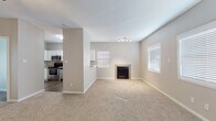 This two-floor residence offers a well-organized layout with thoughtfully selected finishes throughout. The main living area greets visitors through a paneled front door, opening into a spacious, carpet-floored room filled with natural light from multiple windows fitted with white blinds. The living space flows toward a tile-surround fireplace, providing a functional focal point, while a track lighting fixture adds overhead illumination.

Adjacent to the living area, the kitchen is equipped with stainless steel appliances including a range, over-the-range microwave, and dishwasher. White shaker-style cabinetry pairs with granite-style countertops and a stainless steel sink beneath a window. The kitchen flooring transitions to a wood-look surface that continues through the entryway.

The bedrooms feature plush carpeting, ceiling fans, and notable vaulted ceiling height, lending an open, airy feel. Each bedroom includes French doors that allow natural light to filter in. The bathrooms are finished with granite-style vanity countertops, white cabinetry, wood-look flooring, and tub-shower combinations, presenting a clean and cohesive aesthetic throughout the home.