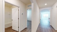 Located at 2771 Lust Rd in Apopka, Florida, this single-story home presents a clean, modern aesthetic defined by neutral tones, wood-look luxury vinyl flooring, and an open, flowing layout. The floor plan connects key living areas through arched doorways and wide corridors, creating a cohesive sense of space throughout.

The kitchen serves as a central hub, featuring white shaker cabinetry, granite countertops, a center island with a sink, recessed lighting, and a full suite of stainless steel appliances including a side-by-side refrigerator, electric range, and built-in microwave. The kitchen opens directly to the living area, which benefits from multiple windows and sliding glass door access, allowing natural light to fill the space.

Bedrooms are generously sized with large windows that invite additional natural light. Bathrooms are finished with granite-topped vanities and white cabinetry; one bathroom includes a tub-shower combination with tile surround, while another features a walk-in shower. A dedicated laundry room accommodates a full-size washer and dryer with overhead wire shelving for storage. The overall ambiance is bright, clean, and move-in ready.
