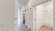 Located at 217 S Weber St in Colorado Springs, CO, this thoughtfully designed one-bedroom, one-bathroom unit offers a clean, contemporary aesthetic throughout its single-floor layout. The open-concept living, dining, and kitchen area forms the heart of the space, bathed in natural light from large windows and a glass door that opens to a private balcony with views of the surrounding neighborhood. The kitchen is well-appointed with stainless steel appliances — including a range, microwave, refrigerator, and dishwasher — complemented by two-tone cabinetry, light quartz countertops, and a classic white subway tile backsplash. Light wood-style flooring runs seamlessly throughout, enhancing the bright and airy feel of the unit. A hallway connects the main living area to the private quarters, featuring a striking sliding barn door that adds a modern-industrial touch. The bedroom is a comfortable retreat with a dedicated closet equipped with wire shelving. The full bathroom includes a tub-shower combo, a wood-toned vanity with stone countertop, and brushed nickel fixtures. An in-unit laundry area adds everyday convenience, making this a fully functional and stylish urban residence.