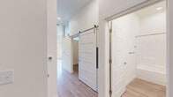 Located at 217 S Weber St in Colorado Springs, CO, this thoughtfully designed one-bedroom, one-bathroom unit offers a clean, contemporary aesthetic throughout its single-floor layout. The open-concept living, dining, and kitchen area forms the heart of the space, bathed in natural light from large windows and a glass door that opens to a private balcony with views of the surrounding neighborhood. The kitchen is well-appointed with stainless steel appliances — including a range, microwave, refrigerator, and dishwasher — complemented by two-tone cabinetry, light quartz countertops, and a classic white subway tile backsplash. Light wood-style flooring runs seamlessly throughout, enhancing the bright and airy feel of the unit. A hallway connects the main living area to the private quarters, featuring a striking sliding barn door that adds a modern-industrial touch. The bedroom is a comfortable retreat with a dedicated closet equipped with wire shelving. The full bathroom includes a tub-shower combo, a wood-toned vanity with stone countertop, and brushed nickel fixtures. An in-unit laundry area adds everyday convenience, making this a fully functional and stylish urban residence.