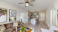 This thoughtfully designed single-story model home in Lady Lake, Florida offers a functional and stylish layout across two bedrooms and two full bathrooms. The open-concept living area is bright and welcoming, with light wood-style flooring, large windows that invite natural light, a ceiling fan, and a glass door providing outdoor access. The kitchen is a standout, outfitted with granite countertops, grey shaker-style cabinetry, a white subway tile backsplash, and a full suite of stainless steel appliances including a range, microwave, dishwasher, and refrigerator. The primary bedroom is generously sized, featuring soft carpet, a ceiling fan, and a distinctive whitewashed brick accent wall. Its en-suite bathroom includes a dual-sink vanity with granite countertops, grey cabinetry, wood-style flooring, and a glass-enclosed walk-in shower. A dedicated walk-in closet with wire shelving completes the primary suite. The second bedroom is equally comfortable, with carpet flooring, a ceiling fan, and ample natural light. The second bathroom features a granite vanity and a tiled tub-shower combination. Two closets provide practical storage throughout the home.