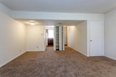 This two-floor residence is designed with functionality and simplicity in mind, presenting a neutral palette of cream-toned walls and wall-to-wall carpeting throughout its living and sleeping areas. The main living space is generously proportioned, featuring a textured ceiling, ceiling fan with track lighting, and a paneled entry door that allows natural light to filter in through its window. The open layout connects seamlessly to a kitchen equipped with dark wood cabinetry, dark granite-style countertops, a white coil-burner range with overhead ventilation hood, and a refrigerator.

The bedrooms are well-sized, carpeted, and fitted with windows dressed in horizontal blinds that provide natural light. Several bedrooms include walk-in or reach-in closets with built-in shelving, offering practical storage solutions. A lower level replicates the spacious layout, with bifold closet doors, additional storage access, and views into the kitchen area.

The bathrooms serve distinct purposes: one features a full tub-shower combo with white subway tile surround and an overhead cabinet, while a second half-bath includes a pedestal sink, mirror cabinet, and tile flooring. Throughout, the space maintains a clean, move-in-ready appearance.