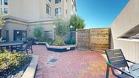 Located on the 8th floor of 639 Geary Street in San Francisco's vibrant Tenderloin/Lower Nob Hill neighborhood, this rooftop deck offers an inviting open-air retreat above the city. The deck is finished with classic herringbone-patterned brick pavers that lend a warm, structured aesthetic to the outdoor space. Generous raised planting beds, bordered with tiled surrounds, feature mature olive trees, ornamental grasses, shrubs, and a variety of greenery that bring a garden-like atmosphere to the urban setting. Globe-style lamp posts are distributed throughout the deck, providing ambient lighting for evening use. Multiple seating areas with outdoor tables and chairs are arranged across the space, offering comfortable spots for gatherings or quiet relaxation. A dedicated BBQ grilling station makes the deck well-suited for outdoor entertaining. A natural wood privacy fence provides a sense of enclosure along one boundary, while the open rooftop exposure affords clear views of the surrounding San Francisco skyline and neighboring buildings. A set of glass double doors connects the deck to the building's interior. The space benefits from abundant natural sunlight and open sky, creating a bright and airy environment ideal for outdoor activities in the heart of the city.