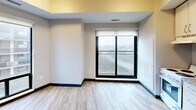 Located at 2346 Weston Rd in Toronto's Weston neighbourhood, this single-floor, one-bedroom, one-bathroom unit offers a efficiently designed layout with modern finishes throughout. Light wood-look laminate flooring runs consistently across all rooms, complemented by crisp white walls, dark baseboards, and recessed lighting that create a clean, contemporary aesthetic.

The unit is accessed through a well-lit hallway lined with white panel doors featuring brushed gold hardware, leading to the various rooms. The bedroom is a comfortable, private space with large windows — including a sliding glass door and a full-height window — that invite natural light and offer views of the surrounding cityscape. Neutral warm-toned walls add a calming atmosphere to the room.

The dining area provides a dedicated space for meals, while the layout is further complemented by two connecting hallways that ensure smooth flow throughout the unit. The full bathroom is neatly appointed with a soaker tub and shower combination, a vanity featuring a granite-topped countertop with under-sink cabinetry, a framed mirror, and overhead lighting. Wood-look flooring extends into the bathroom, maintaining visual cohesion across the entire unit. Overall, the space presents a tidy, move-in-ready environment with practical finishes suited for comfortable urban living.